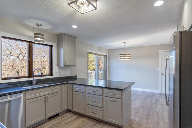 Kitchen featuring sink, gray cabinets, appliances with stainless steel finishes, decorative light fixtures, and kitchen peninsula | Image 44