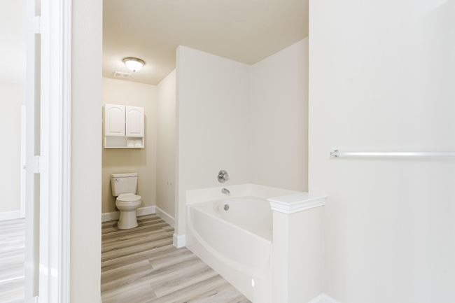Bathroom with baseboards, visible vents, toilet, wood finished floors, and a bath | Image 11
