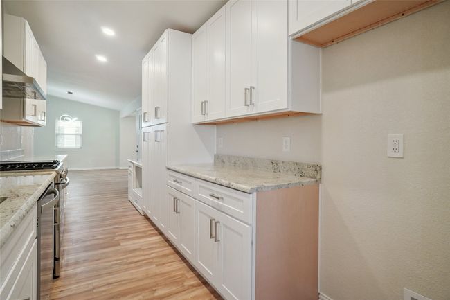 Stunning galley kitchen with custom wood cabinetry, granite countertops, built-in pantry, and upgraded fitxures. | Image 9