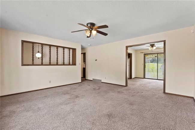 Spare room featuring a ceiling fan, light carpet, baseboards, and a textured ceiling | Image 5