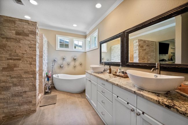 Full bath with ornamental molding, double vanity, a freestanding tub, tiled shower, and tile patterned flooring | Image 15