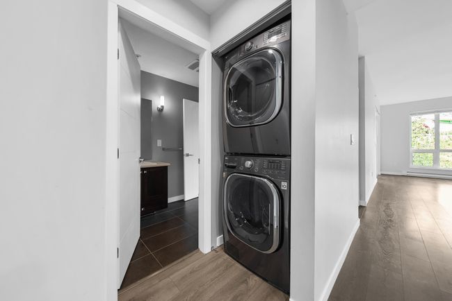 Laundry room with stacked washer and clothes dryer, wood finished floors, and baseboards | Image 36