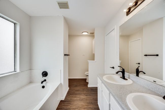 Full bathroom with a bath, double vanity, plenty of natural light, and wood finished floors | Image 33