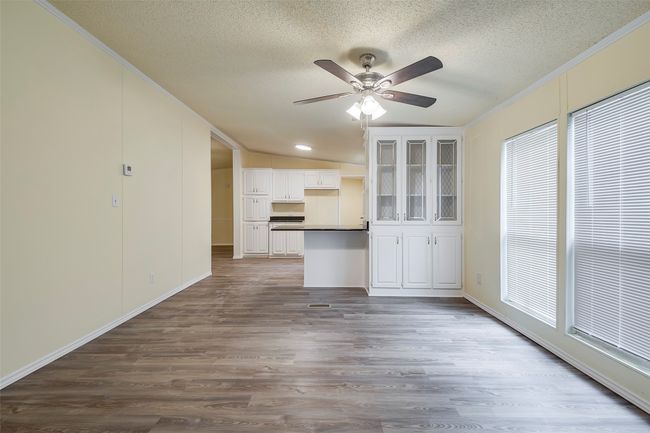 Unfurnished living room featuring a textured ceiling, crown molding, ceiling fan, dark wood finished floors, and baseboards | Image 11