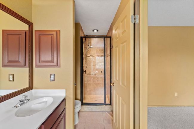 Bathroom with a stall shower, vanity, and tile patterned flooring | Image 30
