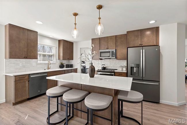 Kitchen featuring stainless steel appliances, backsplash, a kitchen bar, light countertops, and recessed lighting | Image 8