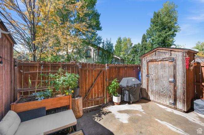 Fenced backyard featuring area for grilling, a storage unit, a gate, a patio, and a garden | Image 22