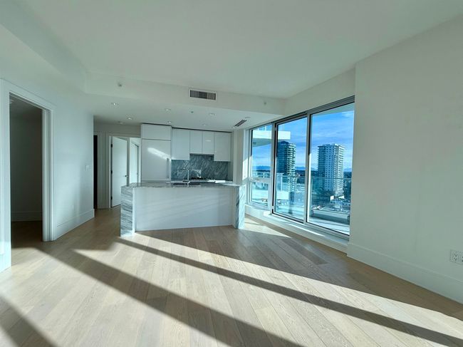 Unfurnished living room with a sink, light wood-style flooring, baseboards, visible vents, and a view of city | Image 6