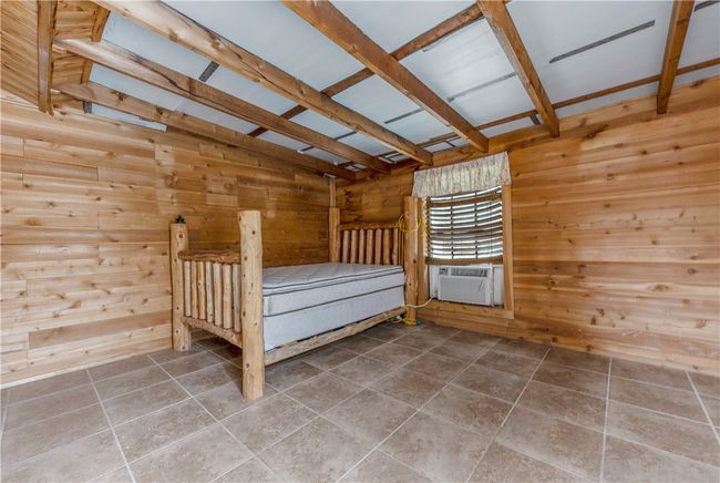 bedroom in pool house with wood walls and cooling unit | Image 28