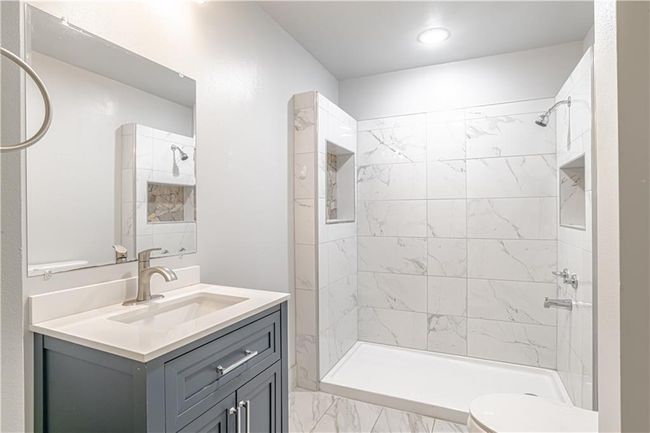 Bathroom featuring vanity, toilet, and tiled shower | Image 31