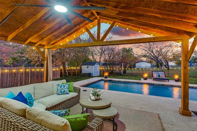 View of pool featuring an outdoor living space, ceiling fan, a fenced backyard, and a storage shed | Image 5