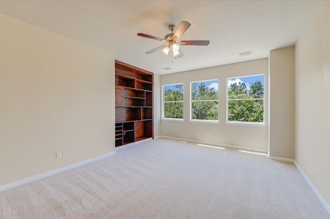 Spare room with built in features, carpet, and a ceiling fan | Image 9