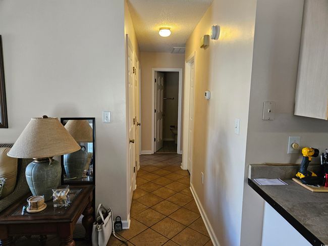 Corridor with tile patterned floors and a textured ceiling | Image 12