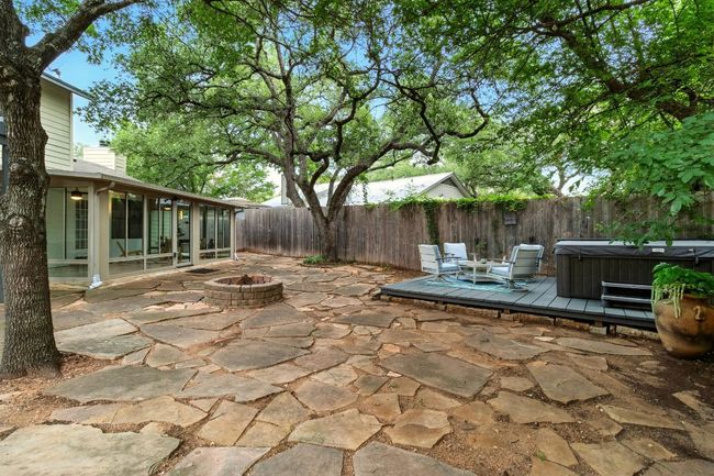 Step outside to your very own backyard oasis. Enjoy evenings around the custom flagstone fire pit, take a soak in the hot tub on its dedicated wooden deck, or dine under the stars on the spacious patio. The oversized side yard offers room for games, pets, or gardening, all under the shade of mature trees | Image 23