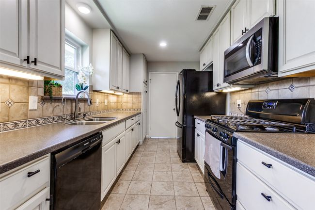 Kitchen featuring black appliances, backsplash, white cabinetry, dark countertops, and recessed lighting | Image 9
