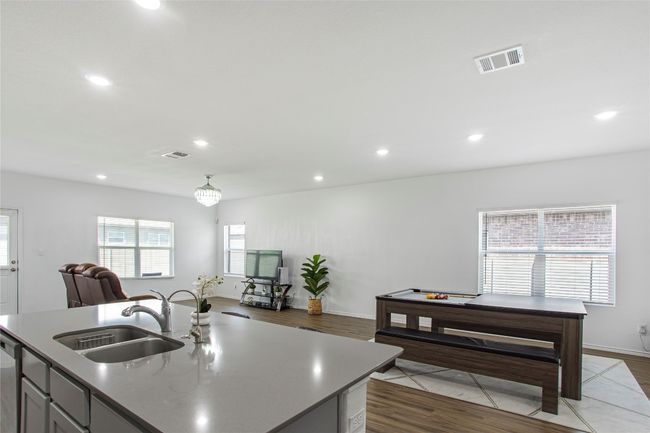 Kitchen with wood finished floors, a sink, open floor plan, visible vents, and recessed lighting | Image 15