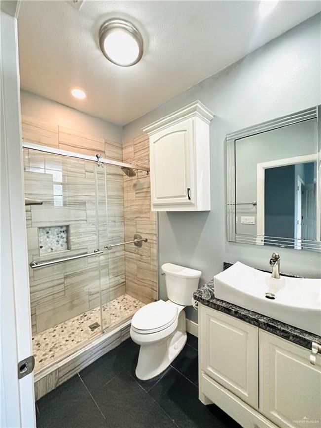 Bathroom with a stall shower, vanity, and tile patterned flooring | Image 18