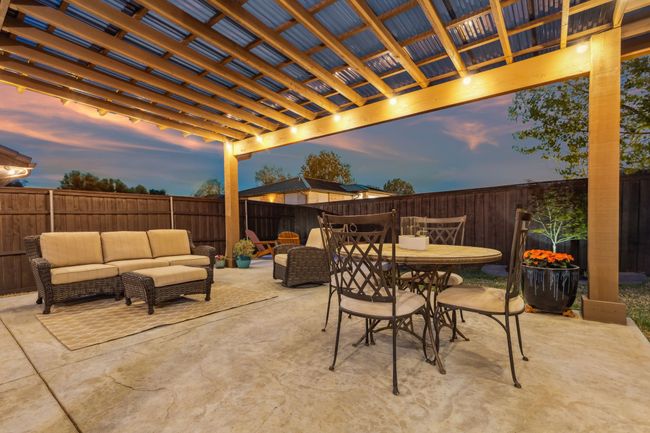 Patio terrace at dusk with outdoor dining area, outdoor lounge area, a fenced backyard, and a pergola | Image 32