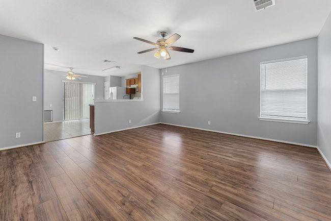 Unfurnished living room with ceiling fan and dark wood-style flooring | Image 5