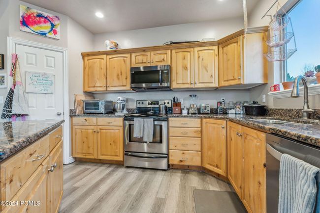 Kitchen with sink, stainless steel appliances, dark stone counters, and light hardwood / wood-style flooring | Image 8