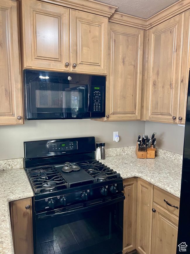 Kitchen with black appliances and light brown cabinetry | Image 26