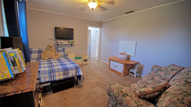 Bedroom featuring a textured ceiling, visible vents, carpet, a ceiling fan, and crown molding | Image 6
