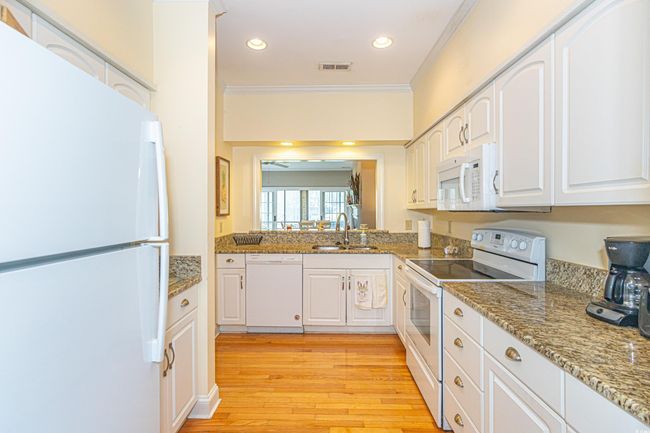 Kitchen featuring visible vents, light wood-style flooring, white appliances, ornamental molding, and a sink | Image 20