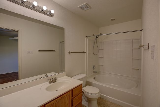 Bathroom featuring toilet, vanity, and washtub / shower combination | Image 8