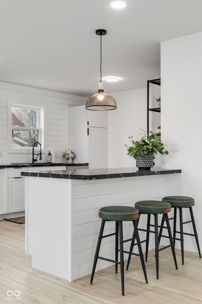 kitchen with a breakfast bar area, light wood finished floors, dark countertops, and white cabinetry | Image 24