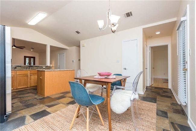 Dining room with stone tile floors, vaulted ceiling, and a chandelier | Image 10