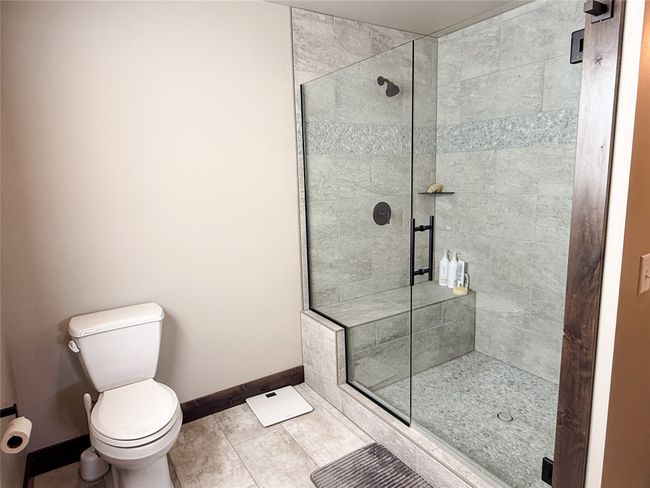 Full bathroom with toilet, a shower stall, baseboards, and tile patterned flooring | Image 17
