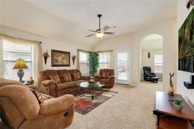Carpeted living room with arched walkways and a ceiling fan | Image 9