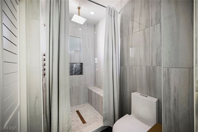 Full bathroom with toilet, tile walls, and a stall shower | Image 57