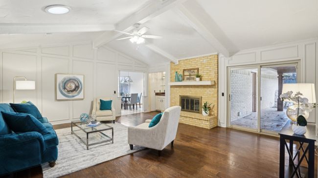 Living room with lofted ceiling with beams, a brick fireplace, dark wood-style floors, and a decorative wall | Image 9