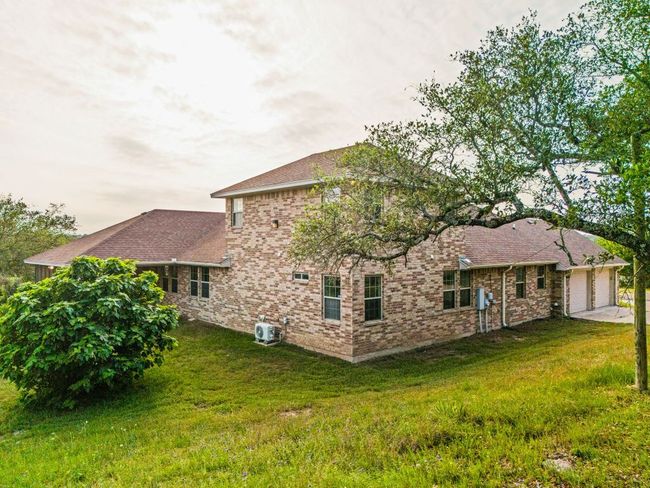 Rear view of house with a garage, brick siding, driveway, and a lawn | Image 38