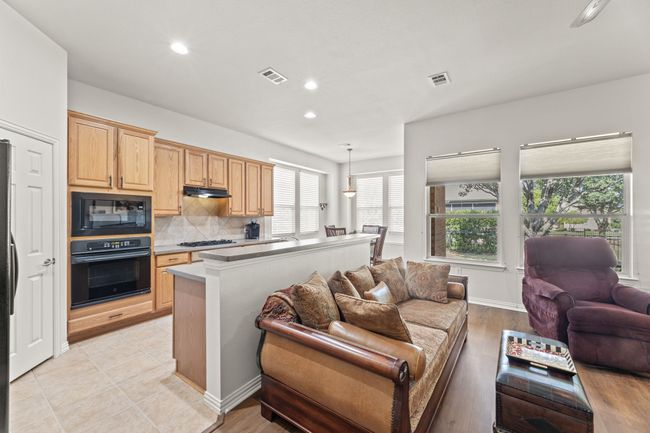 Kitchen with black appliances, open floor plan, light brown cabinetry, recessed lighting, and tasteful backsplash | Image 19