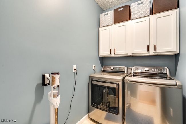Laundry room featuring washer and clothes dryer, cabinet space, and a textured ceiling | Image 21