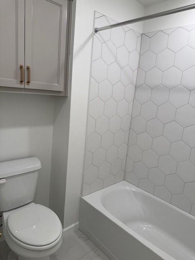 Full bath featuring bathing tub / shower combination, toilet, marble finish floor, and baseboards | Image 31