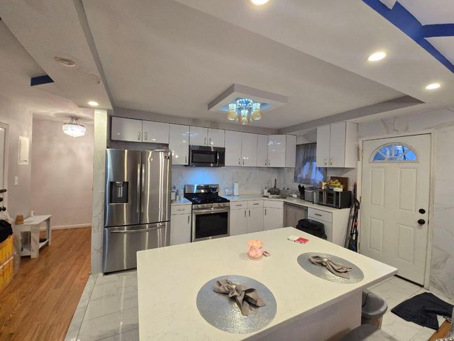 Kitchen with white cabinets, light countertops, appliances with stainless steel finishes, recessed lighting, and marble finish floor | Image 5