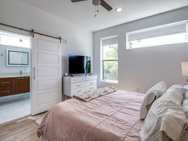 Bedroom with a barn door, ensuite bathroom, recessed lighting, light wood finished floors, and a ceiling fan | Image 20