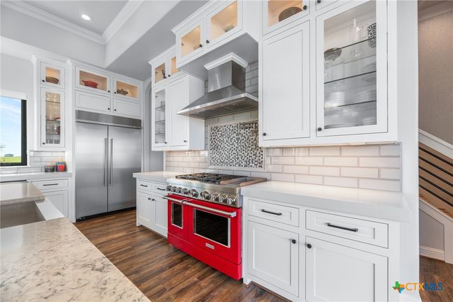 Kitchen with Double Oven Range, Vent Hood, Under Cabinet Lights, and Lighted Glass Cabinets | Image 8