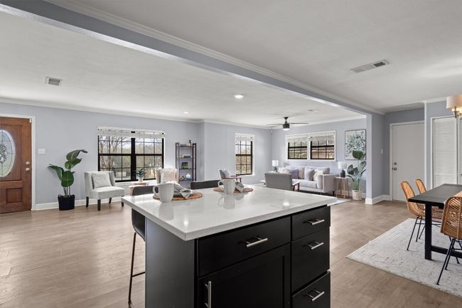 Kitchen featuring visible vents, a breakfast bar, light wood-type flooring, light countertops, and dark cabinetry | Image 15