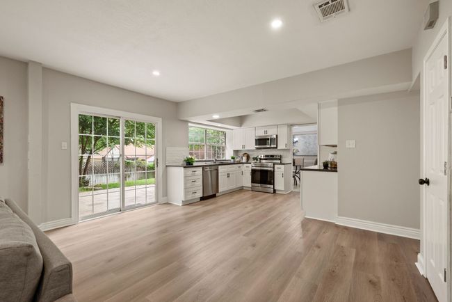The kitchen flows seamlessly into the dining and living areas, which makes this space ideal for entertaining and daily living. The continuity of the light wood flooring enhances the sense of spaciousness. | Image 16