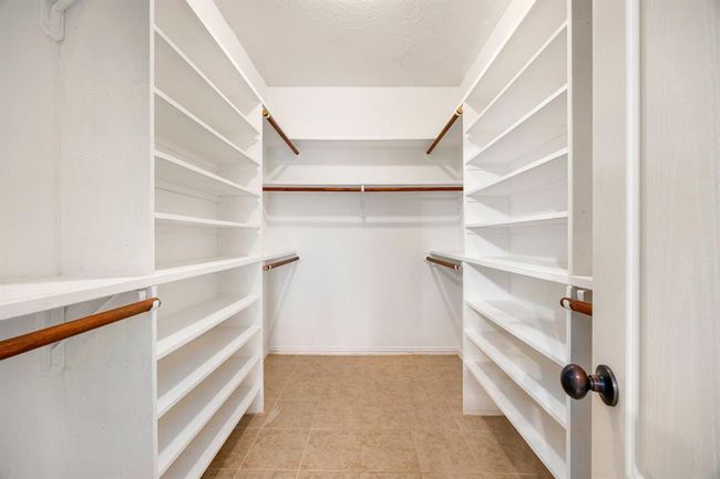 This primary bedroom closet has plenty of storage space for both his and her clothes. | Image 26