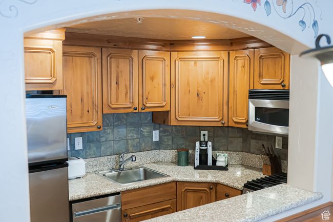 Kitchen featuring stainless steel appliances, tasteful backsplash, a sink, and brown cabinets | Image 10