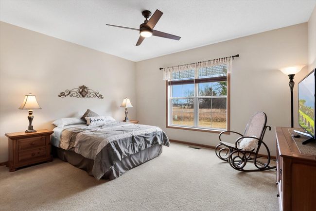 Spacious primary bedroom featuring a large window, modern ceiling fan, and beautiful oak paneled doors. | Image 24