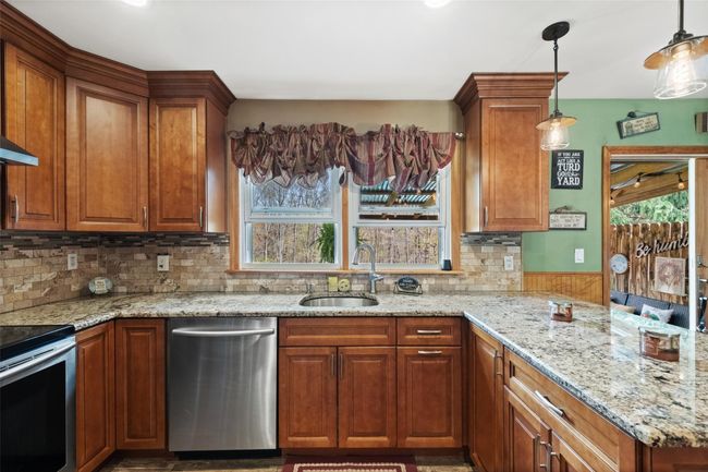 Kitchen featuring light stone countertops, stainless steel appliances, brown cabinetry, and a sink | Image 13