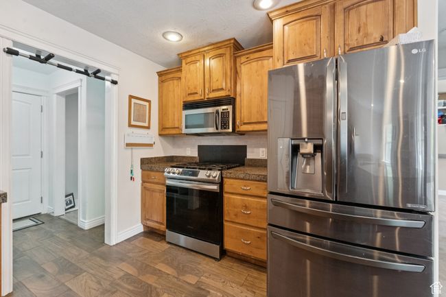 Kitchen with stainless steel appliances, dark countertops, baseboards, brown cabinets, and recessed lighting | Image 10
