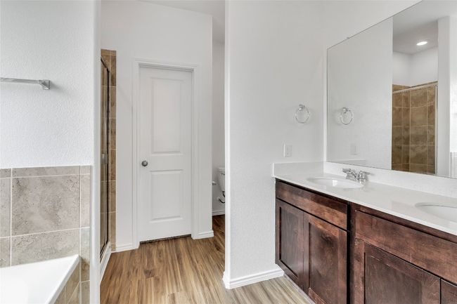 Bathroom featuring double vanity, tiled shower, wood finished floors, and a bath | Image 20