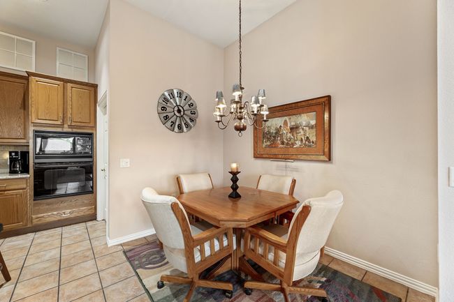 Dining space with a chandelier, baseboards, light tile patterned flooring, and a high ceiling | Image 18